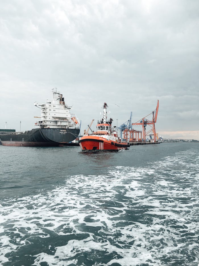 A tugboat guides a cargo ship at a bustling port, emphasizing maritime transport.